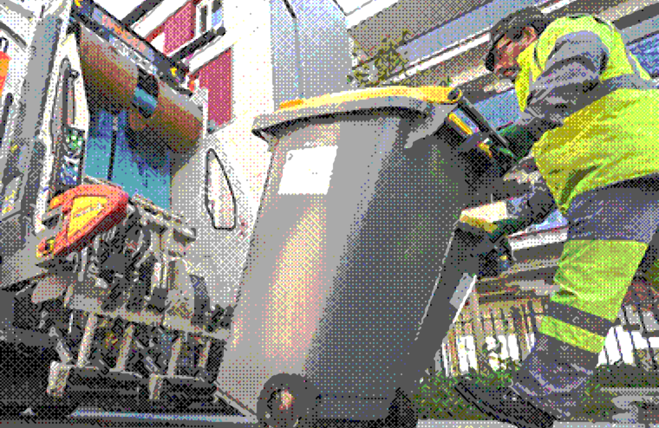 Agent effectuant le ramassage des poubelles derrière un camion benne